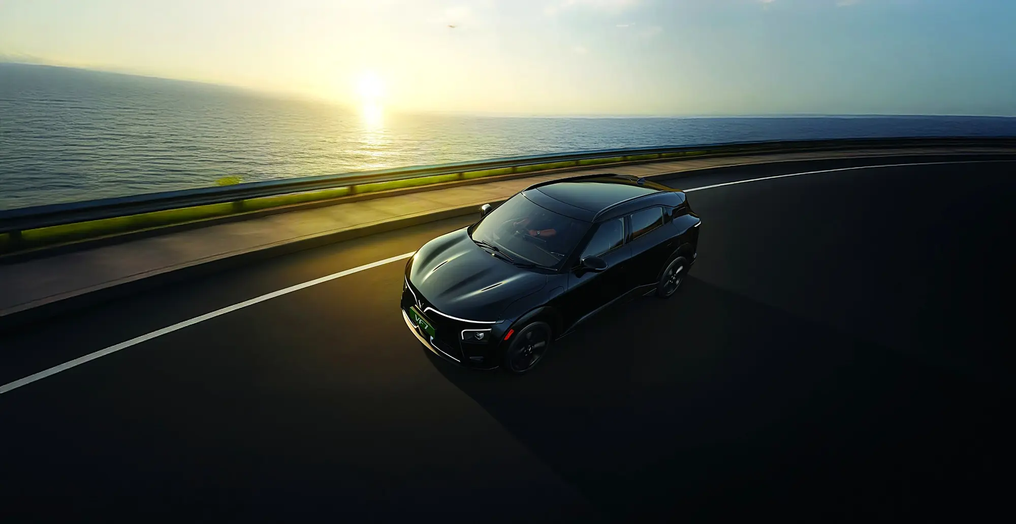 A black VinFast VF 7 on a coastal road at dusk