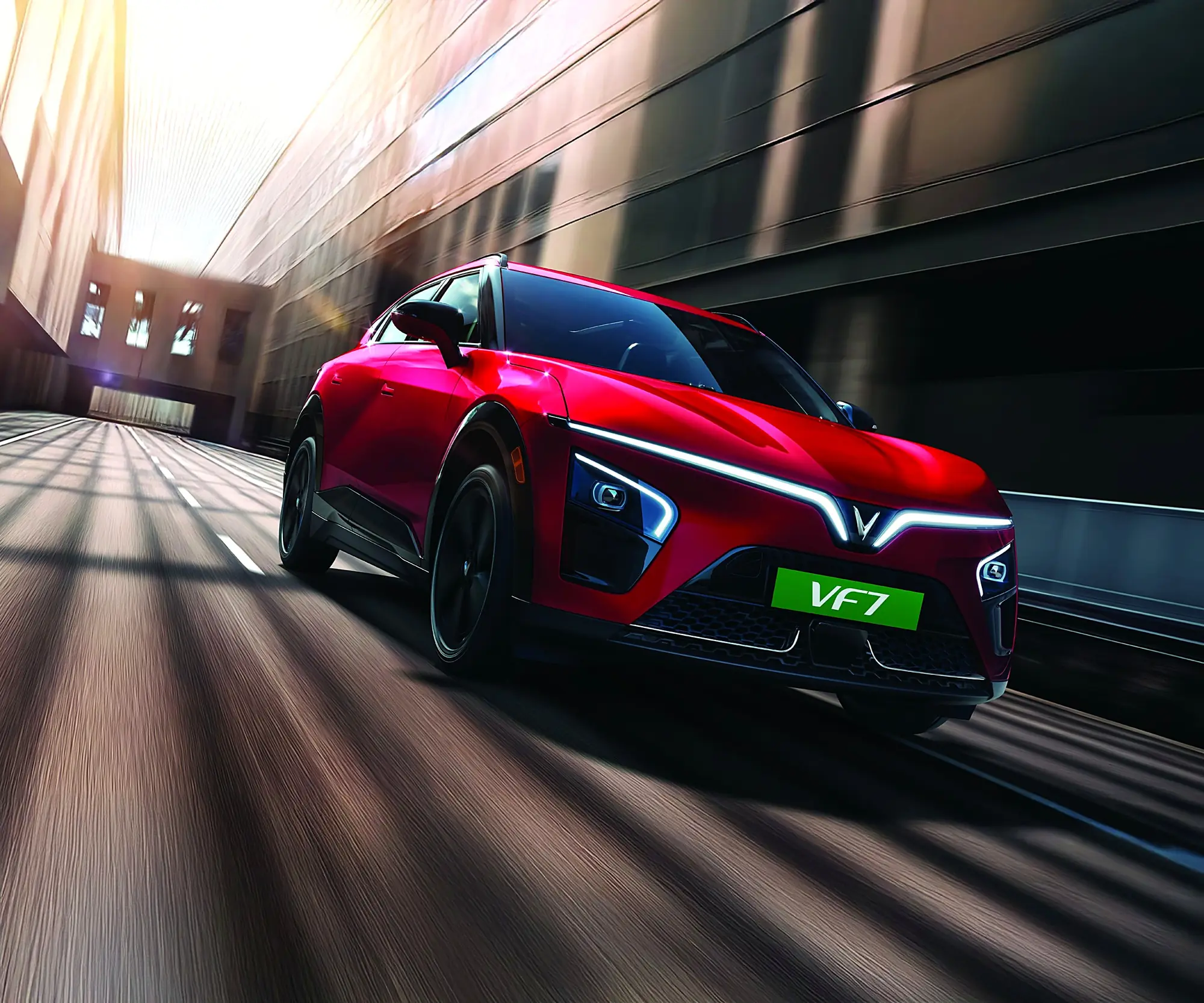 A red VinFast VF 7 driving fast through a city underpass